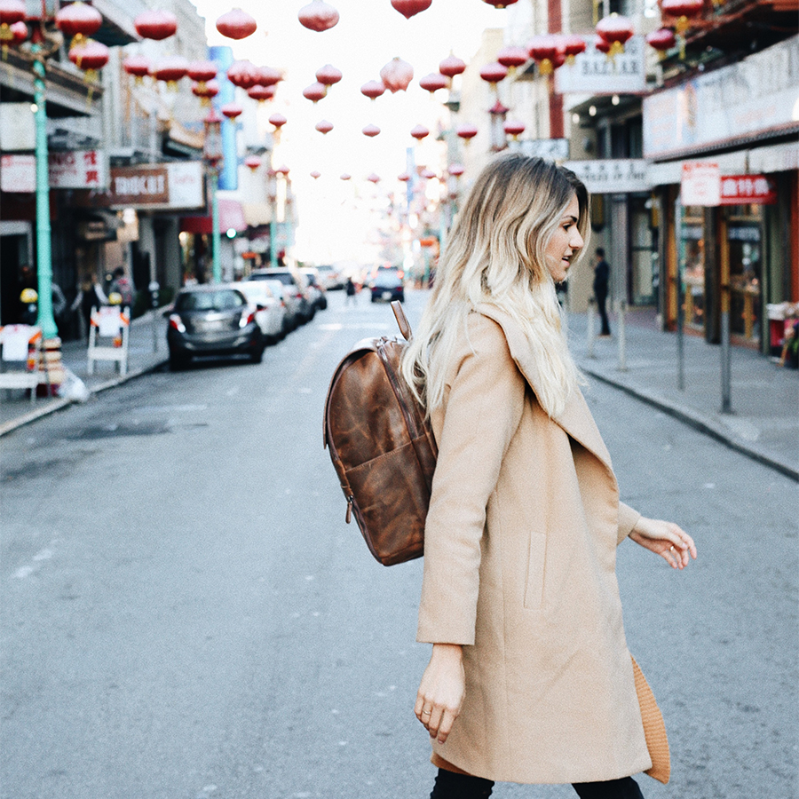 A freelance businesswoman walking with her minimalist leather Atlas Supply Co. backpack.