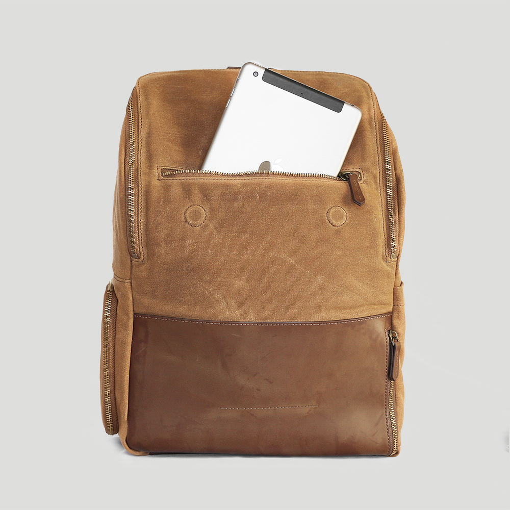 A mixed material unzipped backpack revealing a smart tablet sticking out