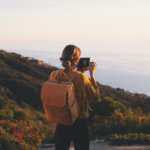 Woman taking photos at dusk while wearing a Atlas Supply Co. camera bag