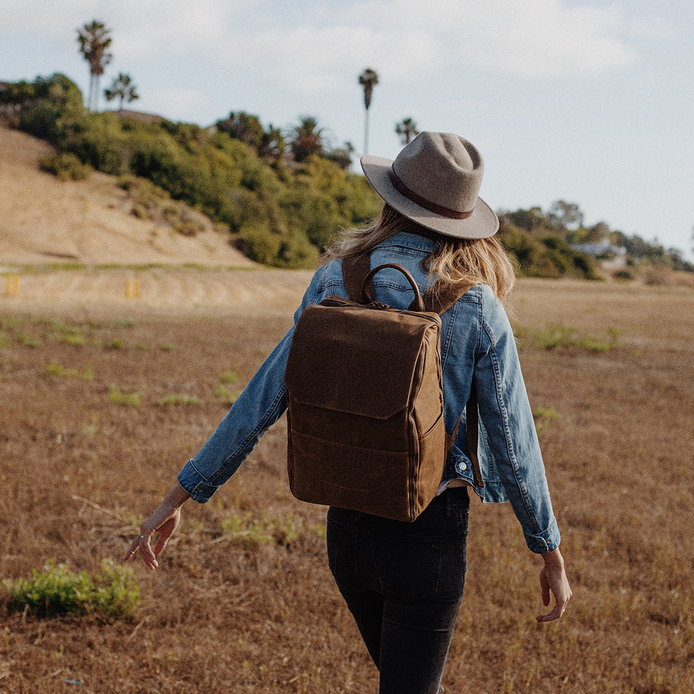  A photographer wearing the Atlas Supply Co. camera bag walks in a field looking for her next photo opportunity.